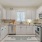 Spacious and well lit kitchen with wood floors and stainless steel appliances. 