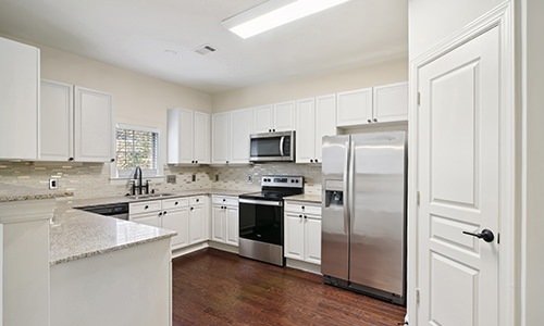 Spacious and well lit kitchen with wood floors and stainless steel appliances